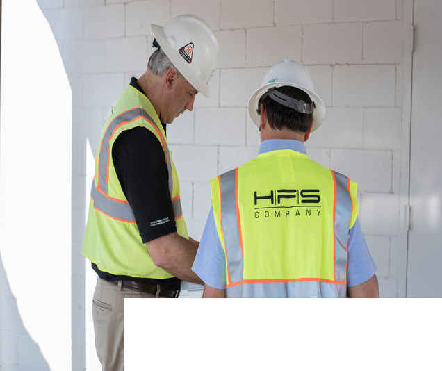 Two engineers wearing hardhats and hi vis vests performing an inspection
